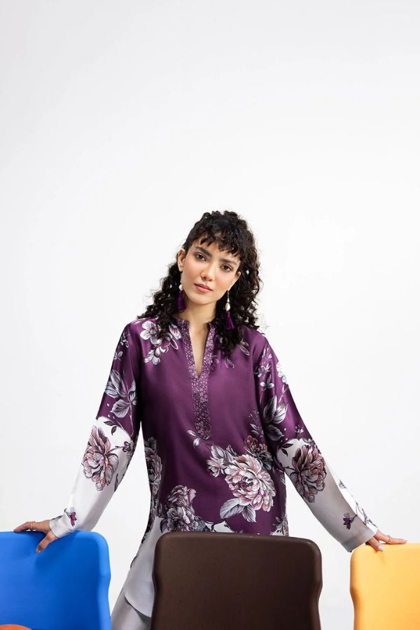 Woman wearing a purple floral blouse with colorful chairs in the background