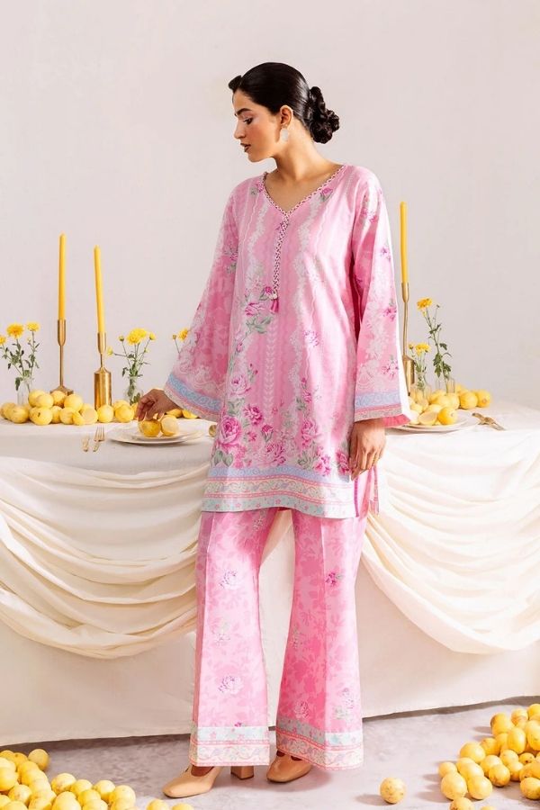 Woman in a pink traditional outfit standing in front of a decorated table with yellow flowers.