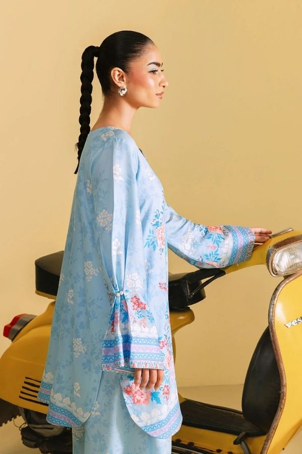 Woman in a light blue floral outfit standing next to a yellow scooter against a beige background
