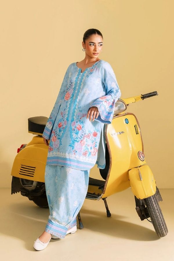 Woman in a light blue traditional outfit standing next to a yellow scooter on a beige background
