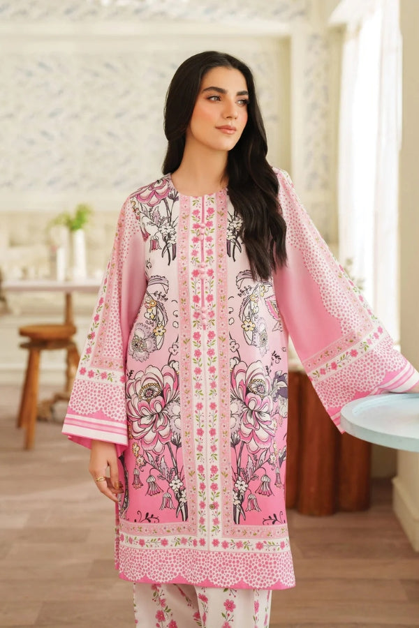 Woman wearing a pink and white patterned outfit in a room with wooden furniture.