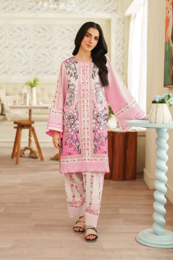 Woman wearing a pink and white embroidered traditional outfit in a decorated room.