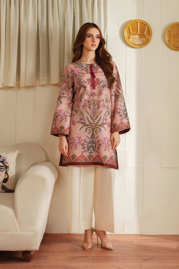 Woman wearing a pink embroidered dress in a living room setting