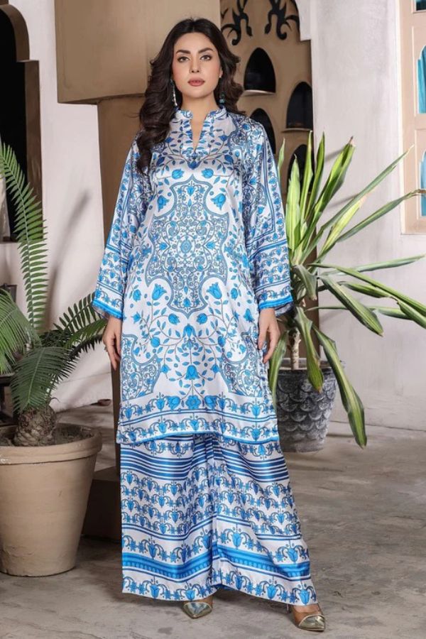 Woman wearing a blue and white patterned outfit standing in a room with plants.