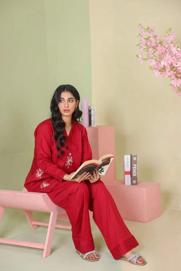 Woman in red outfit reading a book in a room with pink and green decor