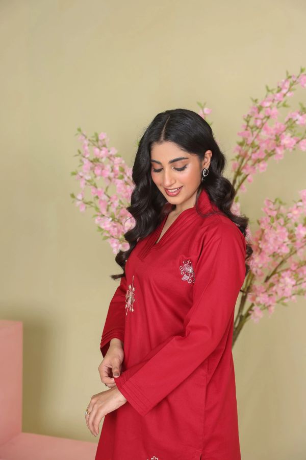 Woman wearing a red outfit with floral decorations against a light green background