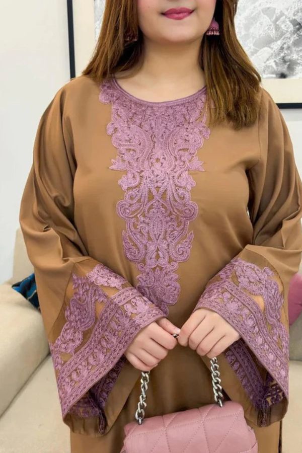 Woman wearing a brown and purple embroidered outfit with a pink handbag.