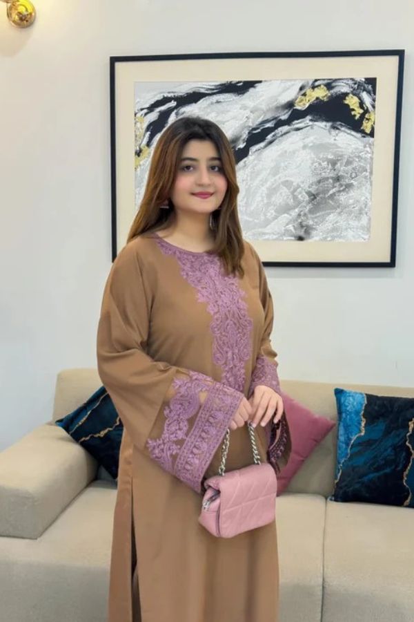 Woman in a brown and purple dress sitting on a couch with a painting in the background