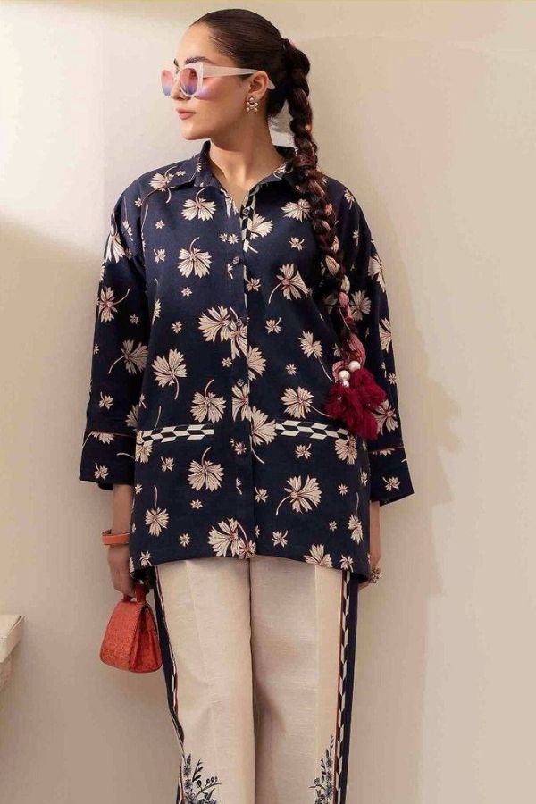 Woman wearing a navy floral blouse with white pants against a plain background