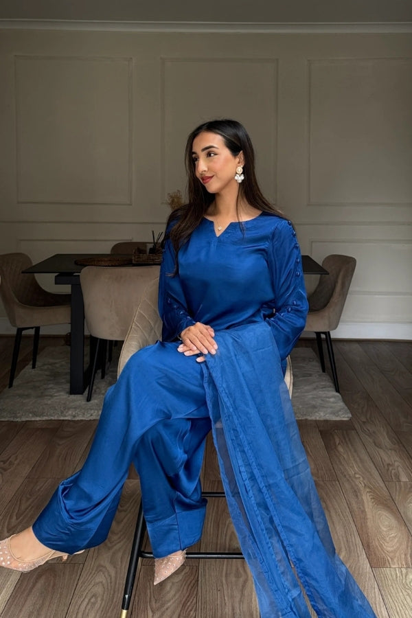 Woman in a blue outfit sitting in a room with neutral decor