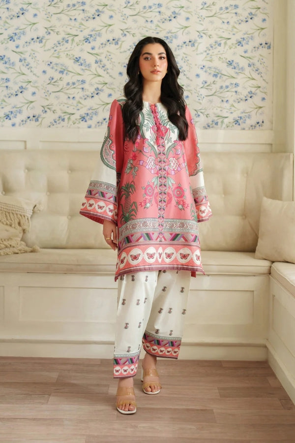 Woman wearing a pink and white embroidered outfit in a decorated room.
