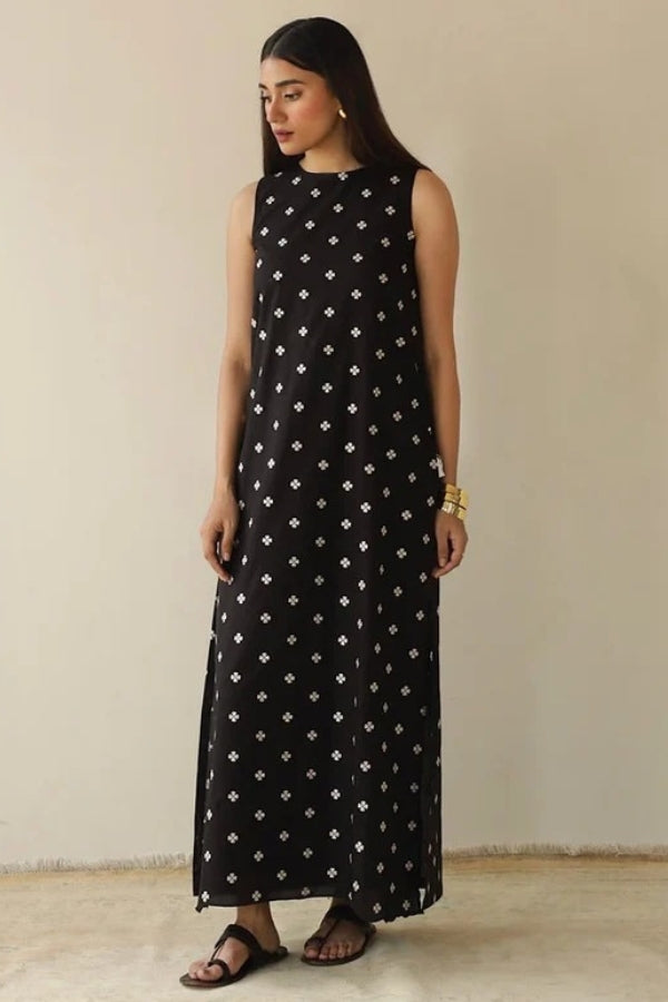 Woman wearing a black sleeveless dress with white patterns on a beige background