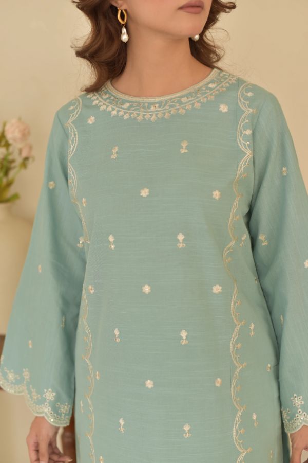 Light blue embroidered dress worn by a person against a beige background