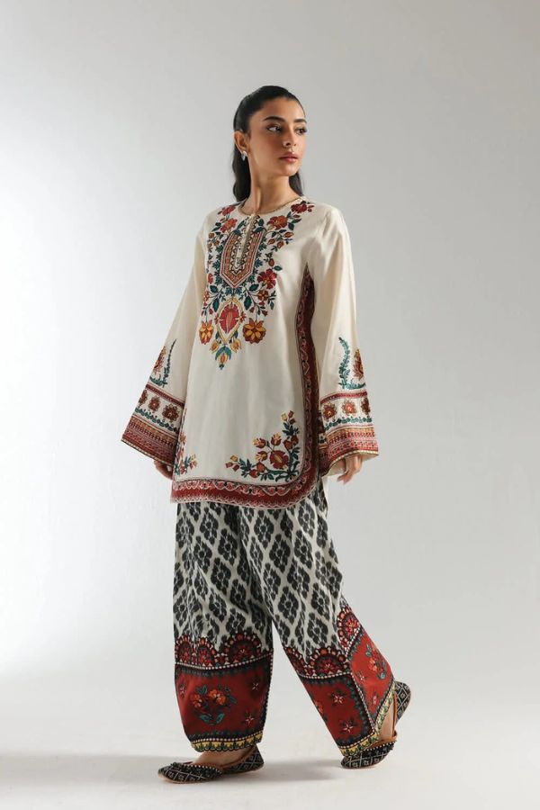 Woman wearing a traditional embroidered outfit with a white background