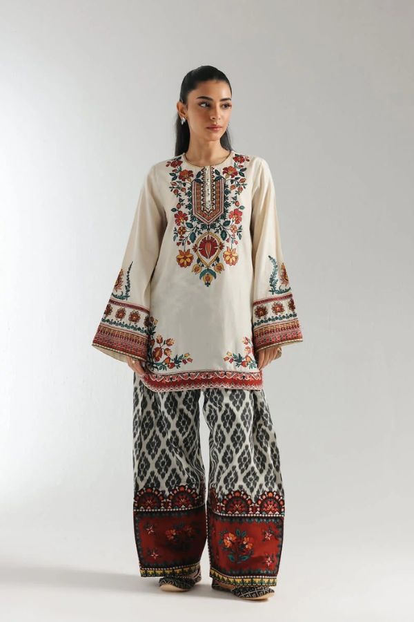 Woman wearing a traditional embroidered outfit with a plain background