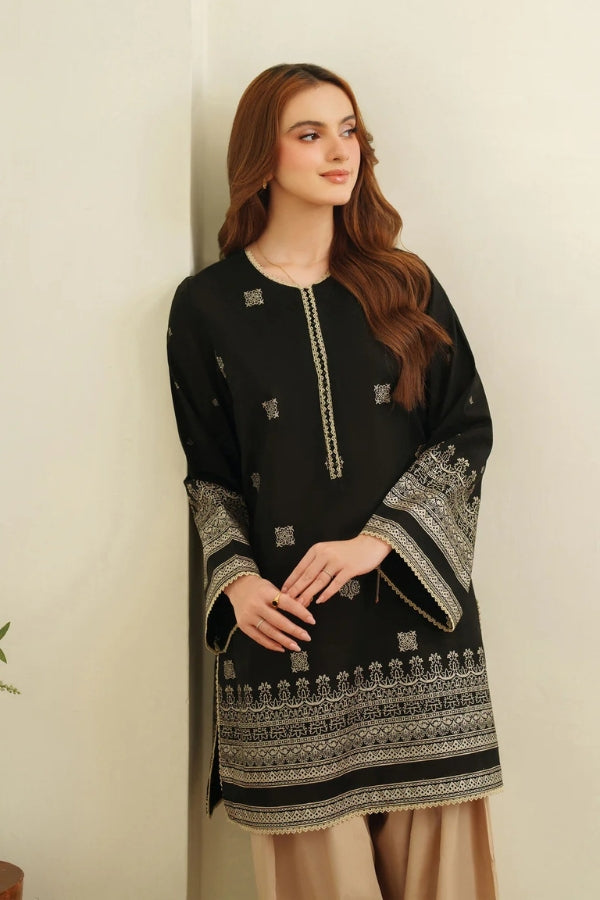Woman wearing a black embroidered dress with a beige background