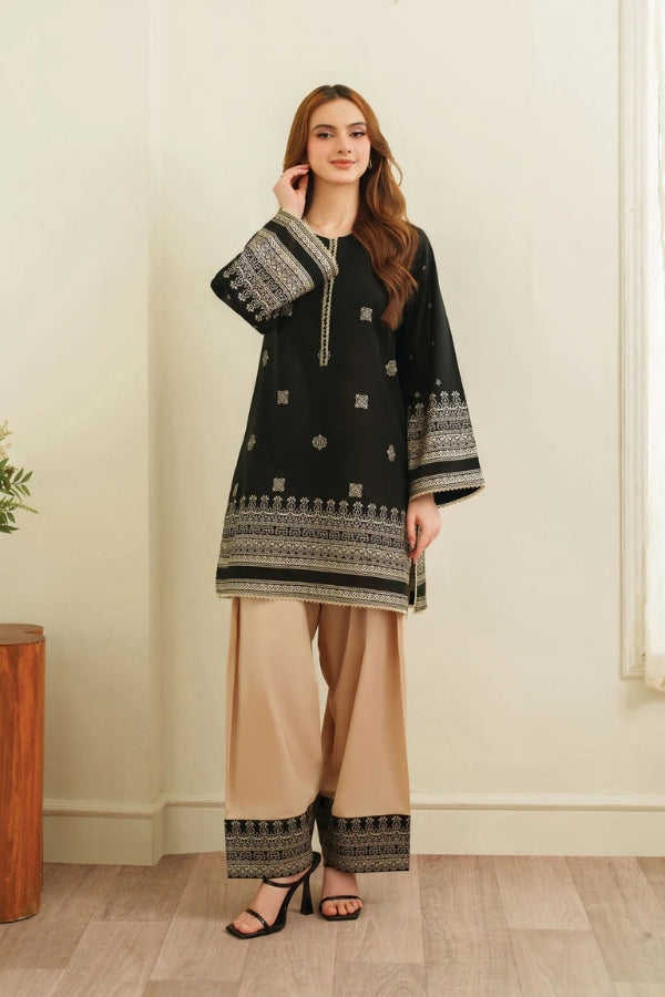 Woman wearing a black and beige traditional outfit with a white wall background