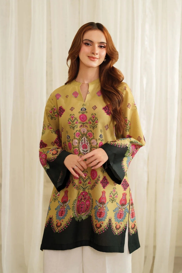 Woman wearing a yellow Printing shirt with black sleeves against a white curtain background